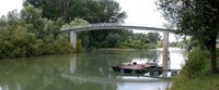 Auch am Althrein in Erfelden wird Müll eingesammelt. Zu sehen ist der Altrhein in Erfelden, über den eine Fußgängerbrücke geht. Die Ufer auf beiden Seiten sind mit Büschen bewachsen.
