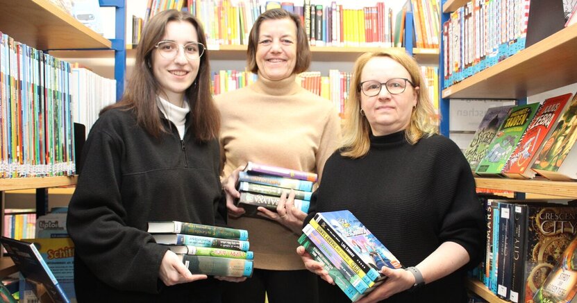 Bücher sind ihre Leidenschaft: Das neue Team der Stadtteilbücherei Goddelau mit Yarisha Garcia Raß, Barbara Niepoth und Sonja Laber (v.li.) Yarisha Garcia Raß, Barbara Niepoth und Sonja Laber (v.li.) stehen zwischen Bücherregalen in der Bücherei Goddelau. Sie haben jede einen Stapel Bücher in der Hand.