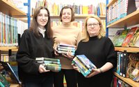 DasTeam der Stadtteilbücherei Goddelau mit Yarisha Garcia Raß, Barbara Niepoth und Sonja Laber (v.li.) steht zwischen Bücherregalen. Alle drei Frauen haben Bücherstapel in der Hand.