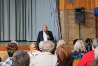 Bürgermeister Marcus Kretschmann steht vor der Bühne und hat ein Mikro in der Hand.